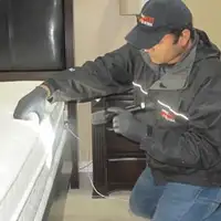 Bed bug inspection technician checking a mattress and bed frame for signs of infestation in Jackson, MS