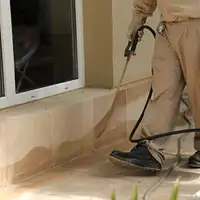 General pest control technician spraying exterior perimeter around a home in Jackson, MS