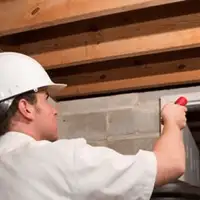 Termite inspection technician checking a basement wall and framing for termite activity in Jackson, MS