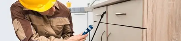 Roach exterminator applying treatment under kitchen cabinets in Jackson, MS